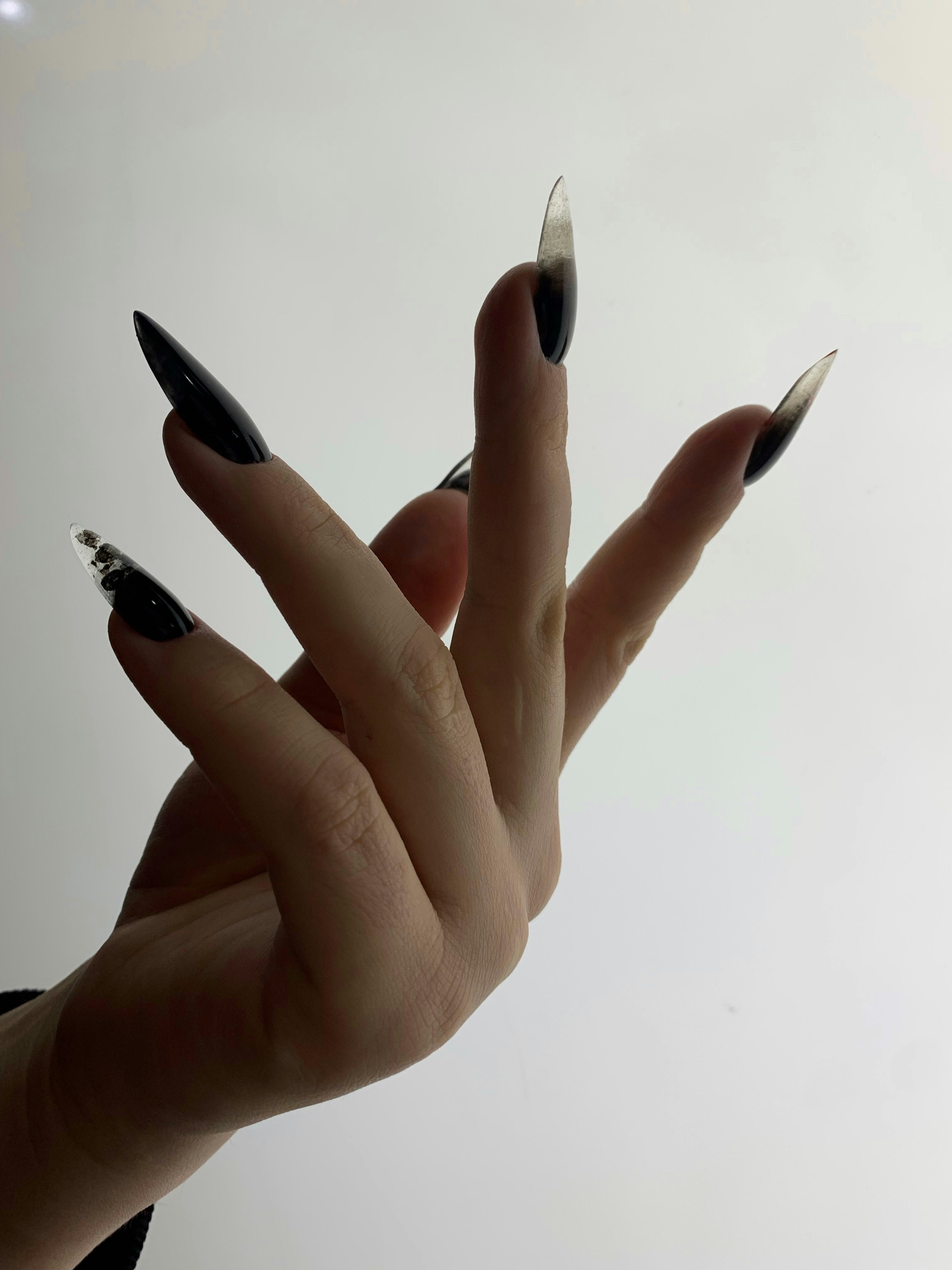 A hand fanned out showing glossy black stiletto nails